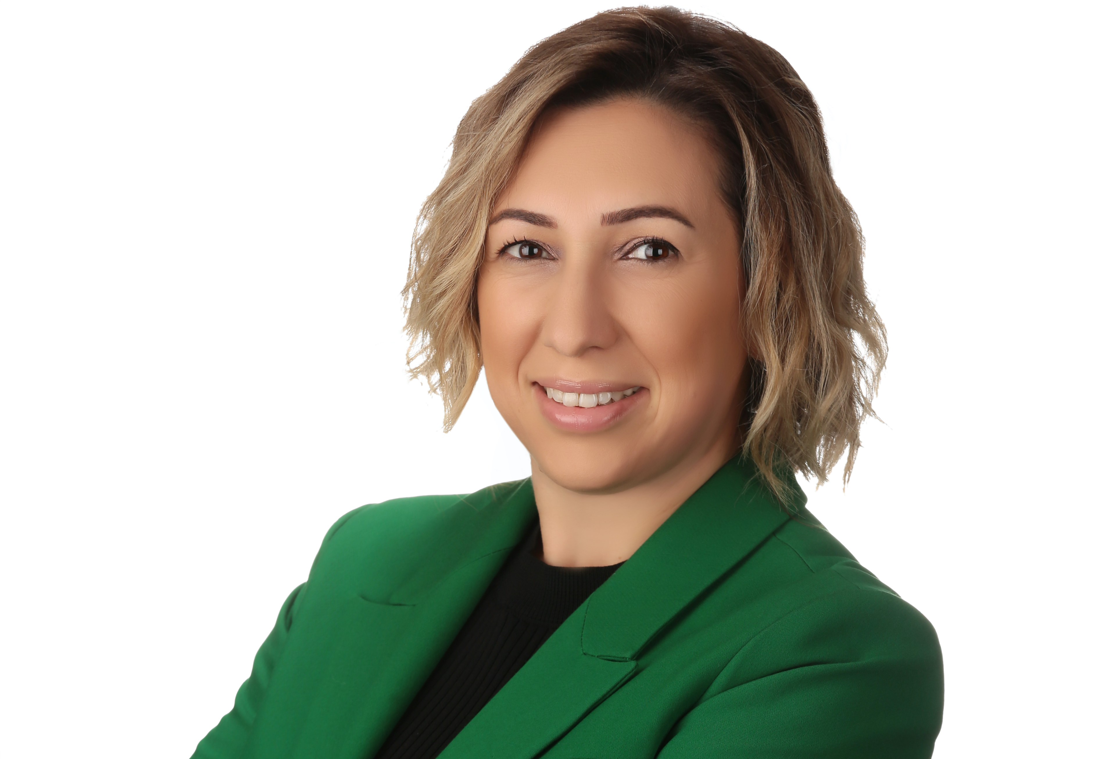 Seyma is a light-skinned woman with blonde hair wearing a green blazer. Her arms are crossed.