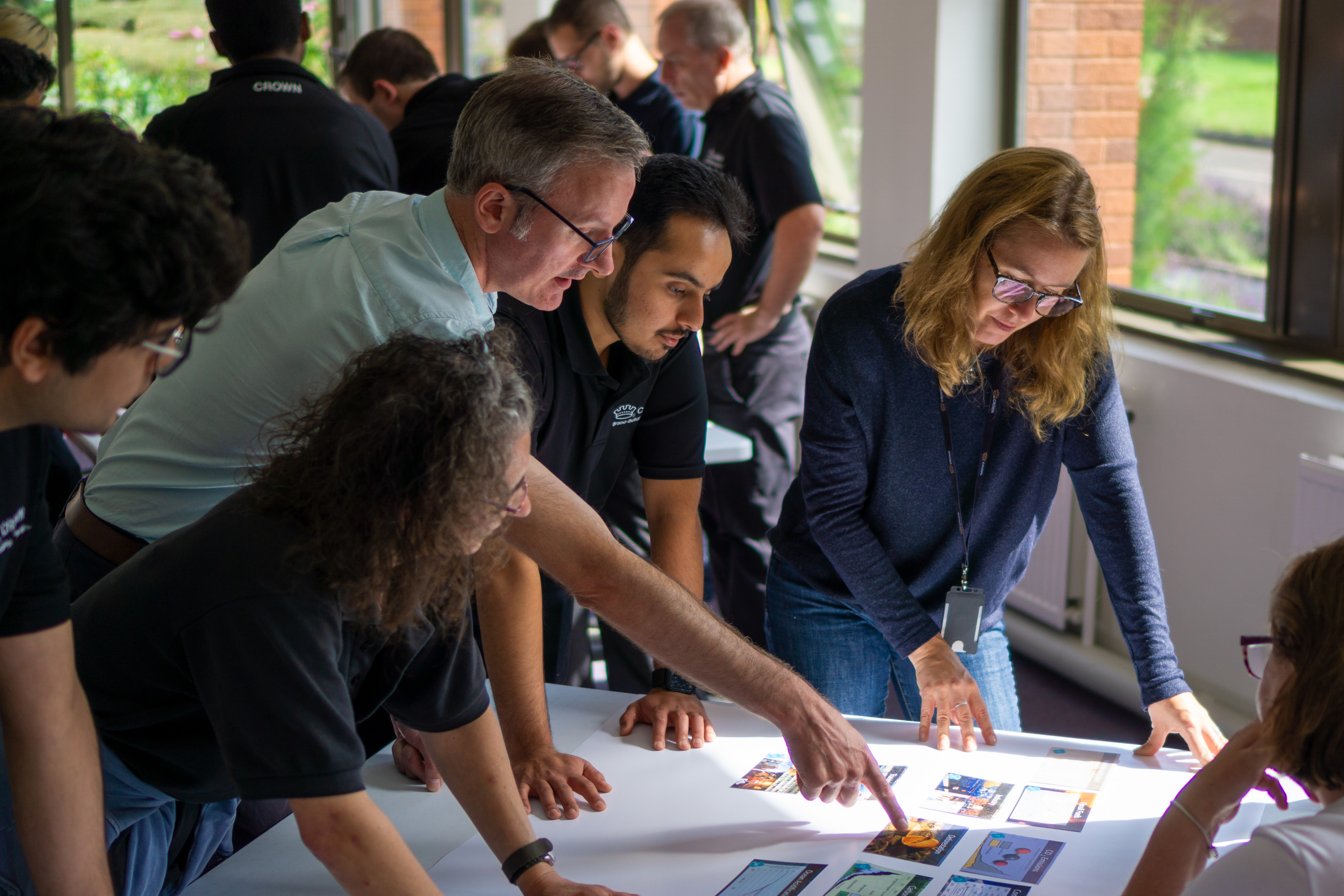 A diverse group of people dressed in business-casual clothing rearranging several charts and graphs on a desk.