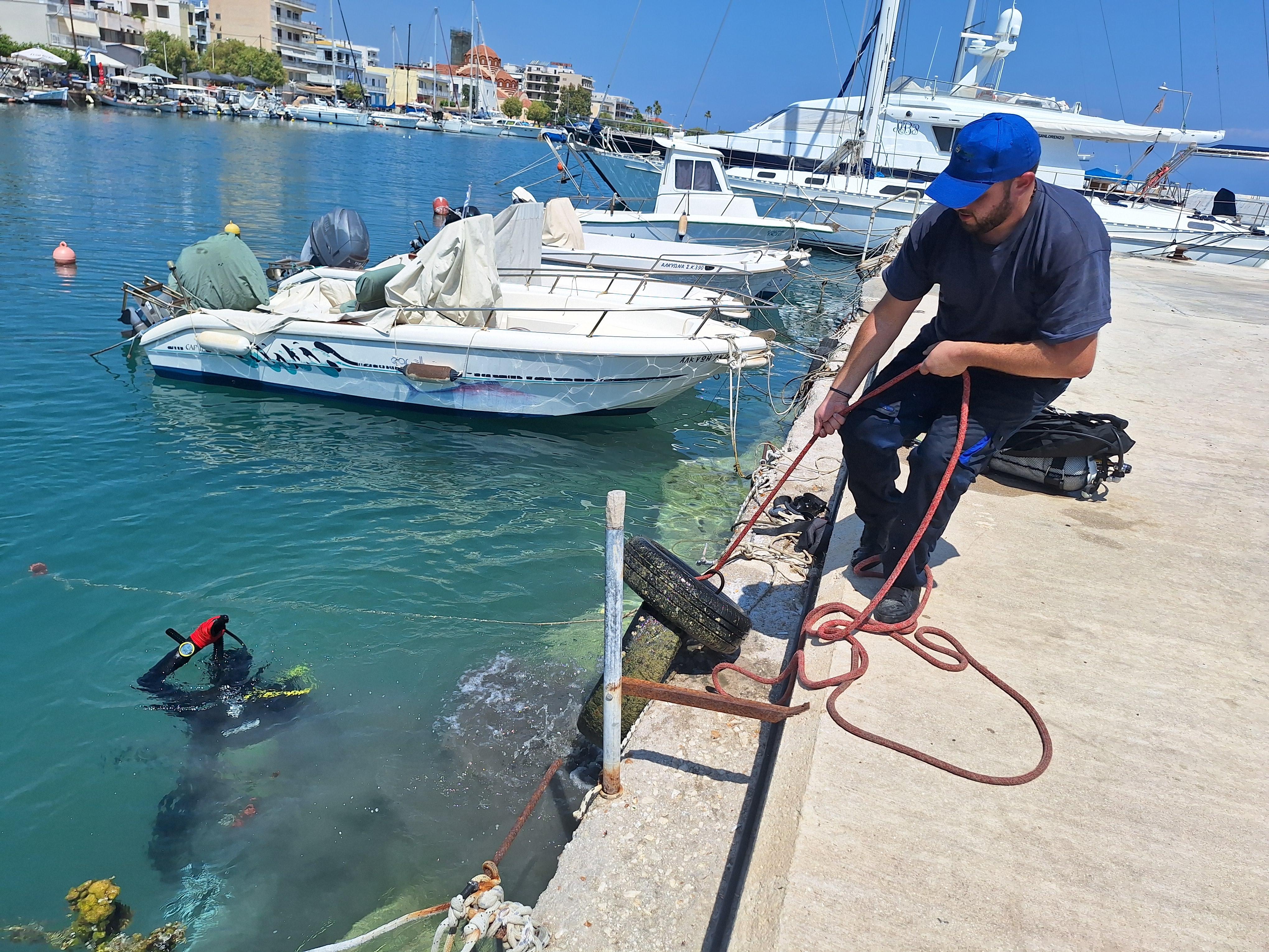 Man pulling tire out of water, while driver continues to look for more trash