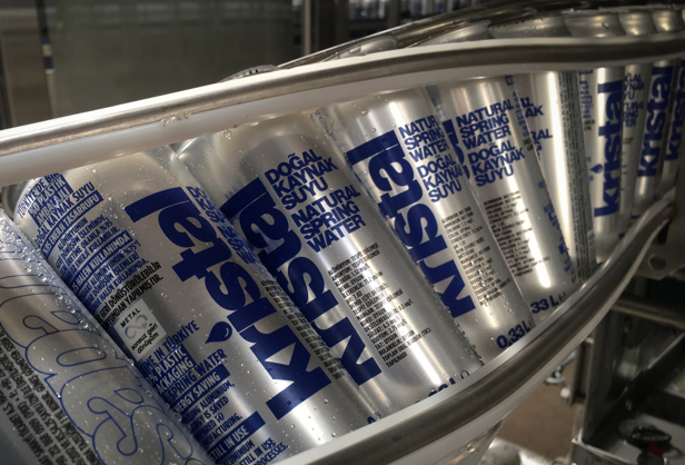 Several aluminum beverage cans with Kristal branding moving through a conveyer belt.