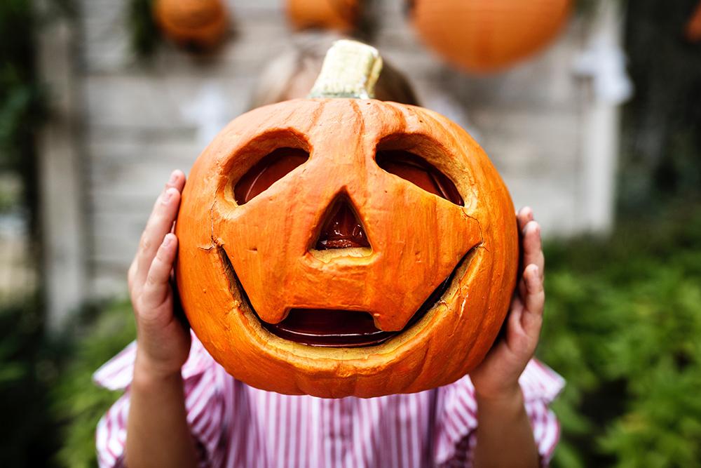 Person holding an orange jack-o-lantern