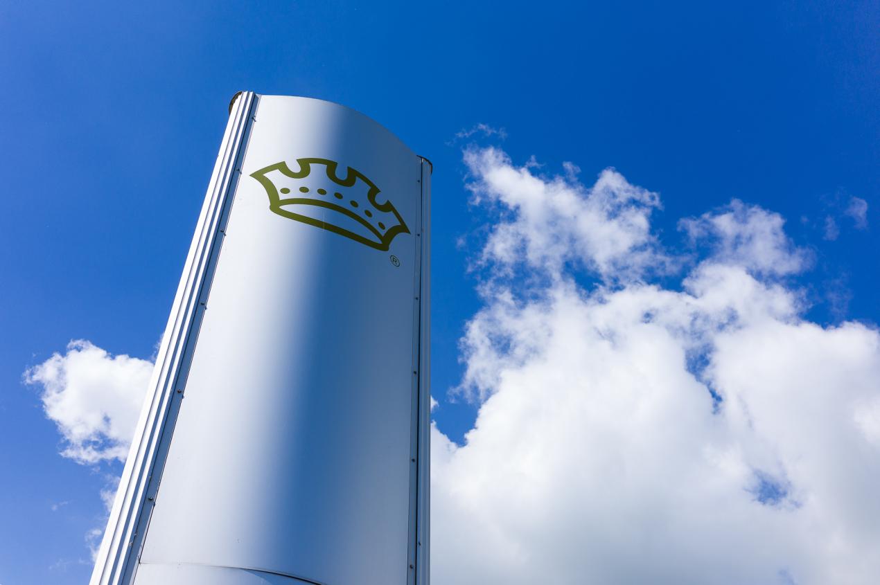 Crown logo against a cloudy sky