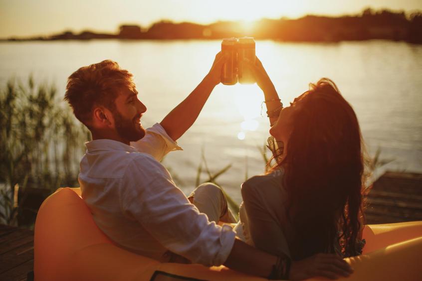 Two people clink glasses outdoors.