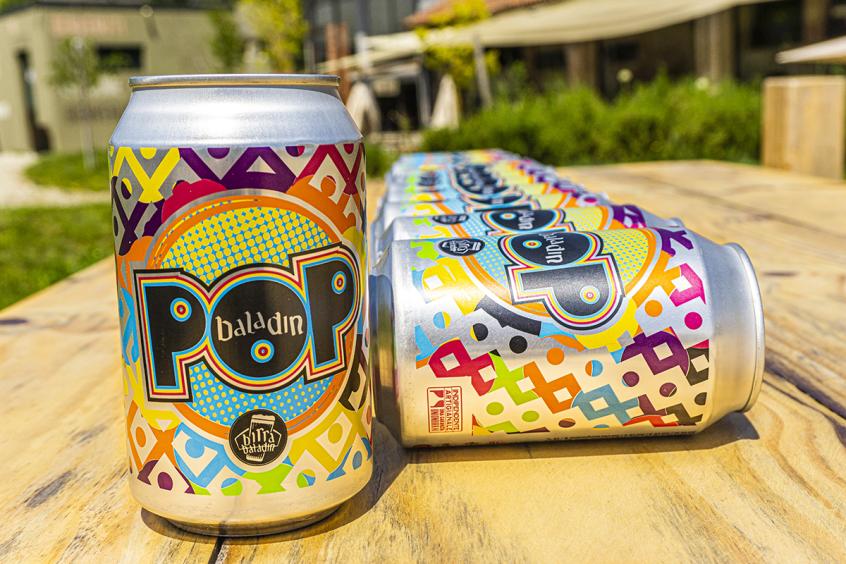 Colors craft beer cans lined up on a wooden table.