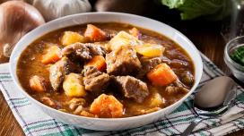 A big bowl of stew sits on a flannel placemat.