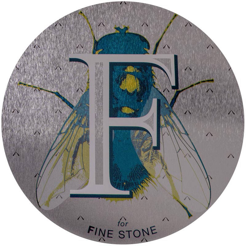 Fine-Stone-2x.jpeg A fine stone surface, decorated with a large letter "F" with a drawing of a large fly behind the F.