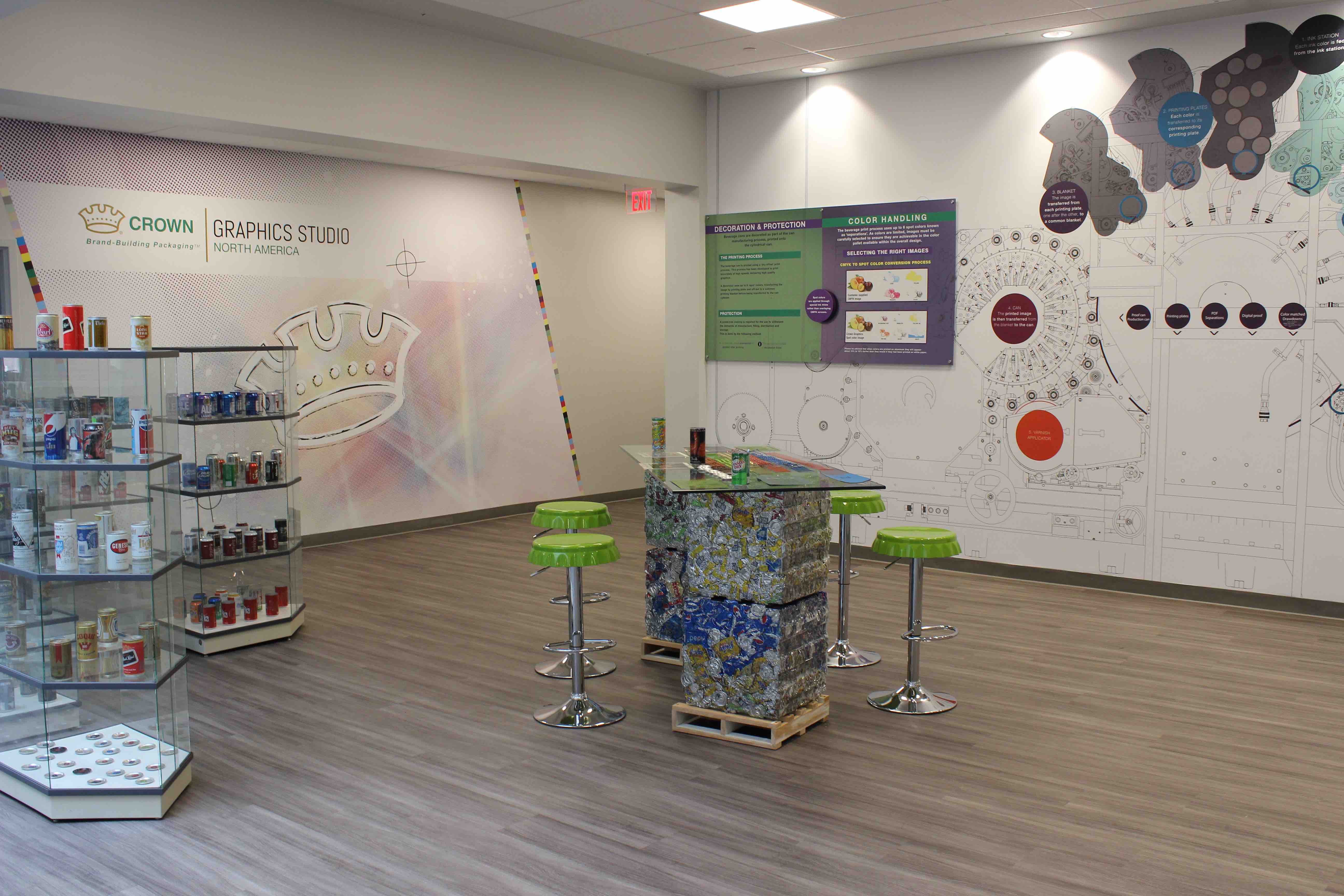 Image of the exhibition area in the Crown studio. Graphics and information on the walls. Chairs and table in the center of the room.