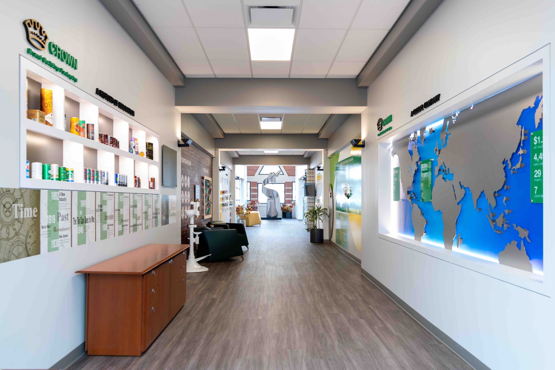 Image of a hallway in the Crown Cork building. A world map on the right and various Crown cork can products on the left. 