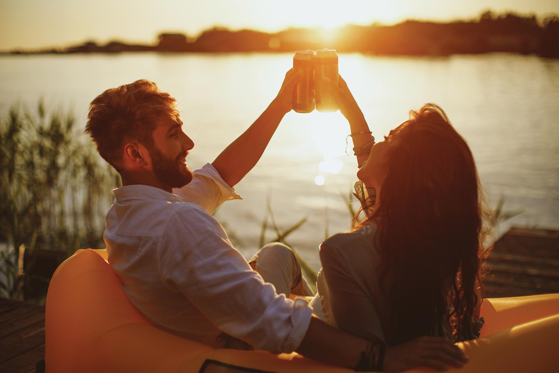 Two people clink glasses outdoors.