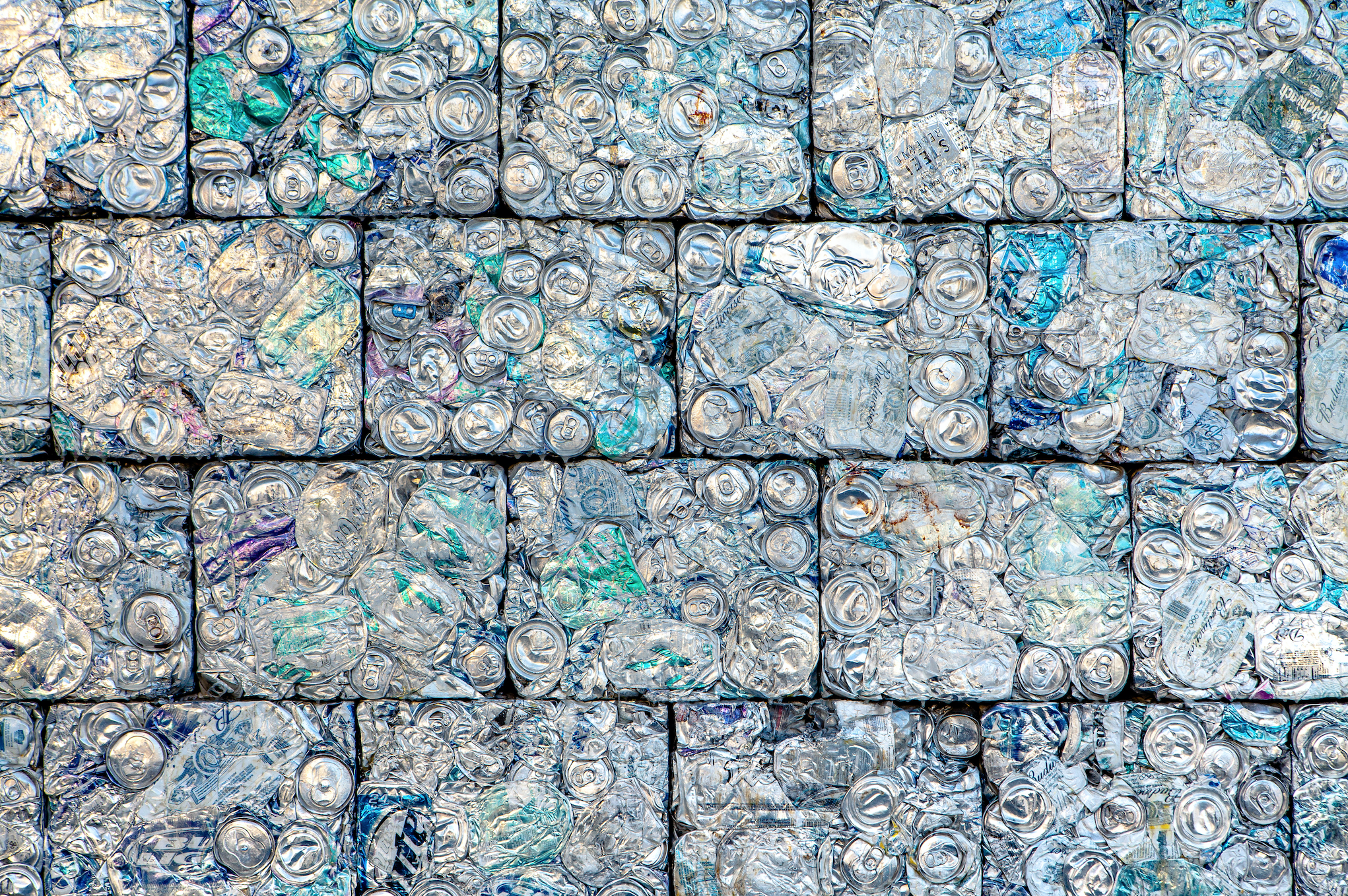 4 rows of aluminum cans that have been crushed into cubes to create a brick wall type look