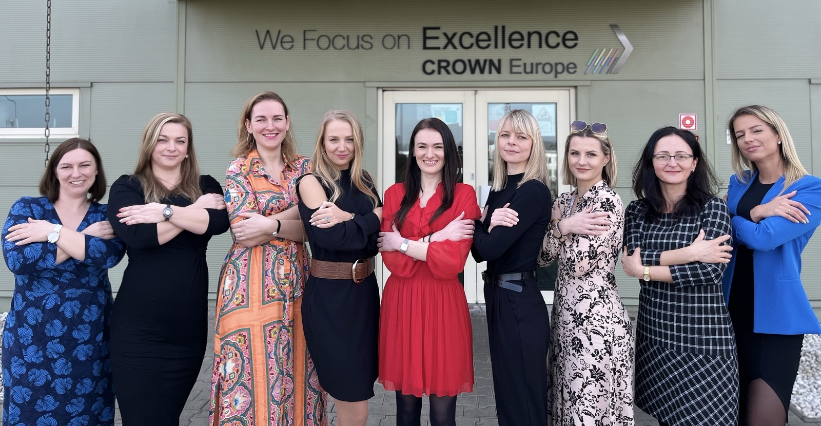 Group of women looking at camera outside Crown building with folded arms