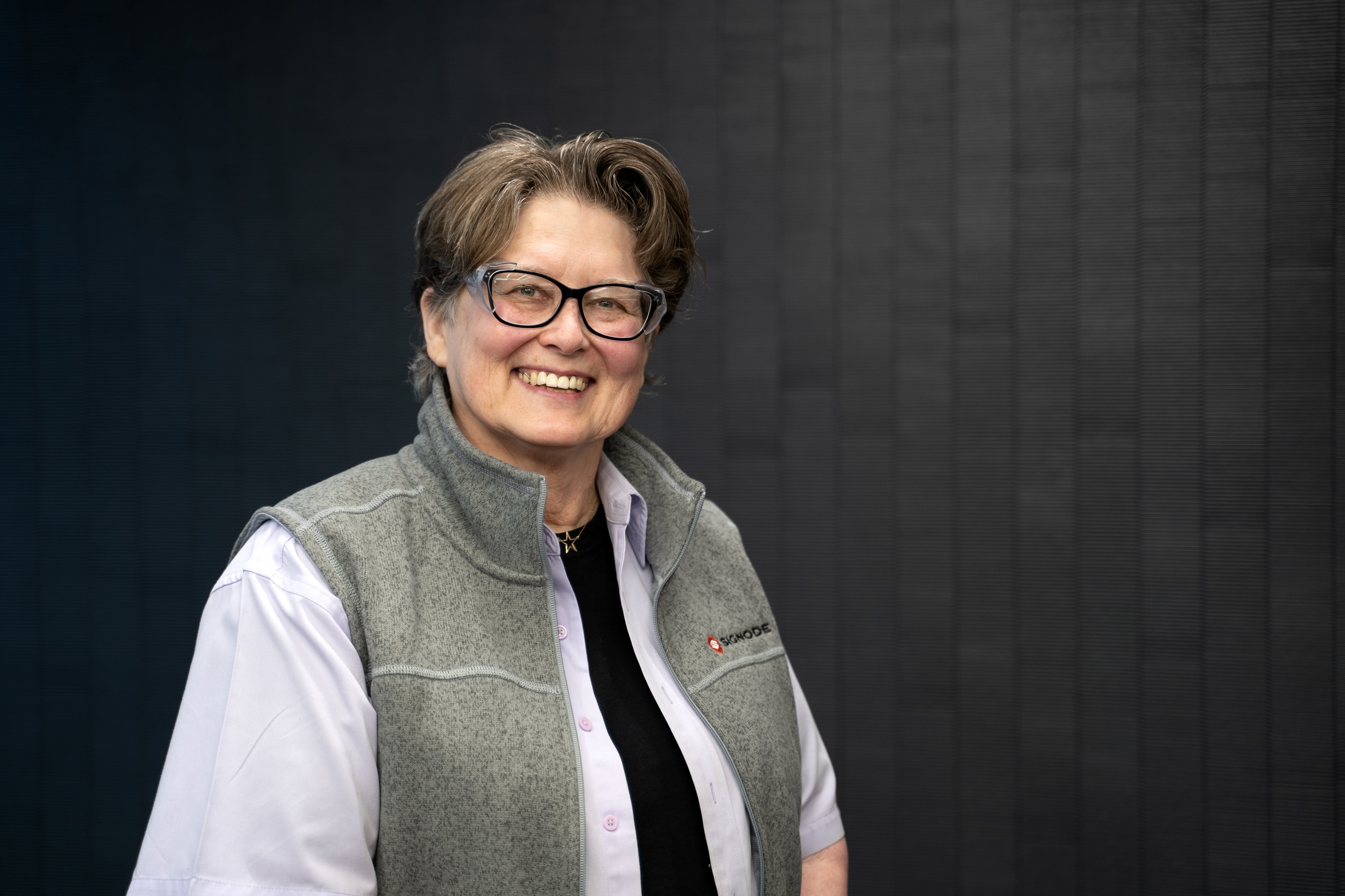 Gloria is a light-skinned woman with dark hair and glasses. She is smiling and friendly.