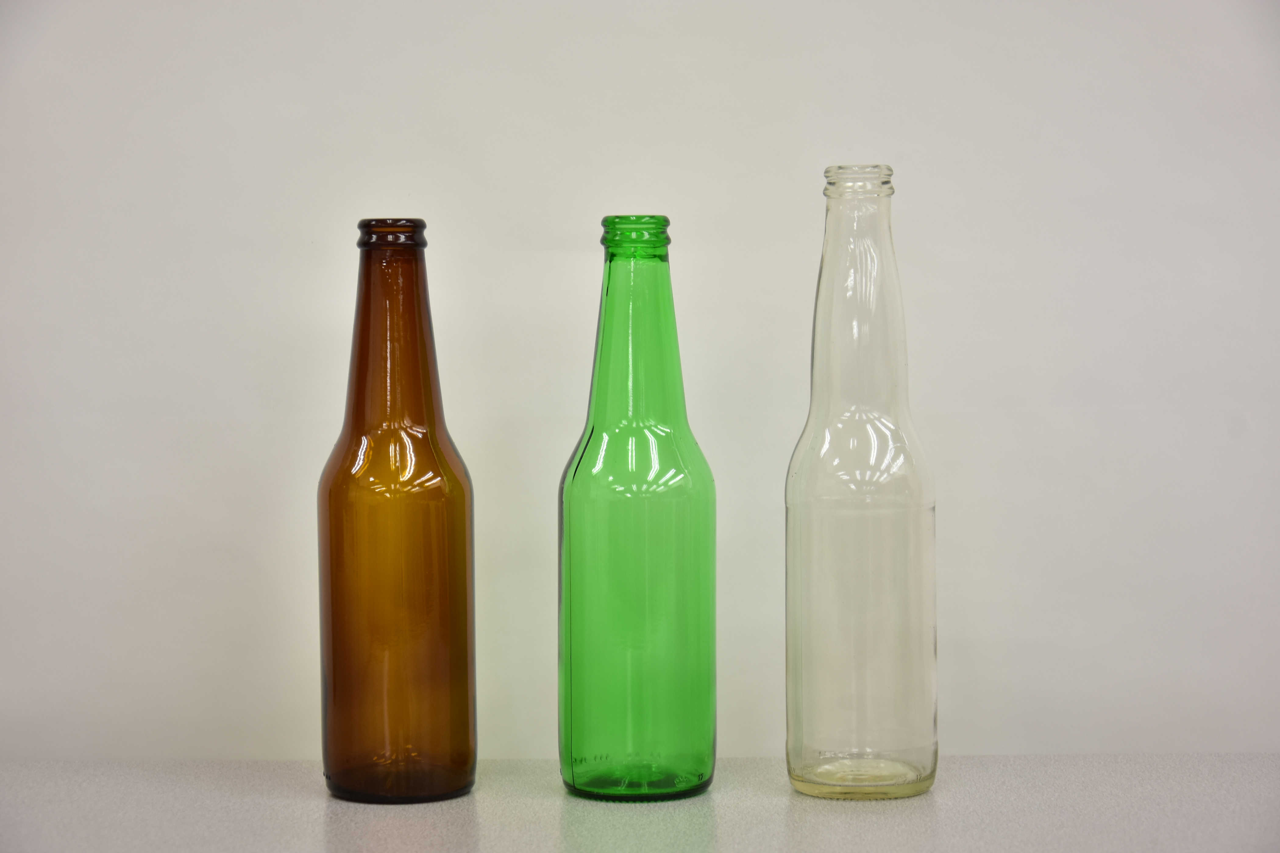 A brown, green, and clear glass bottle of varying heights