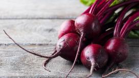 A collection of several beets sitting on a rustic wooden table.