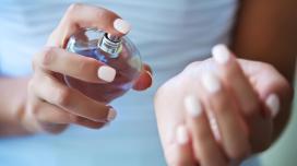 A closeup of a person spraying perfume onto their wrist..
