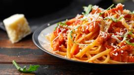 A closeup of a plate of spaghetti on a plate with spaghetti sauce, mozzarella cheese, and basil.