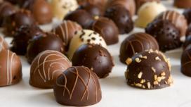 Several small chocolate balls sit on a piece of parchment paper.