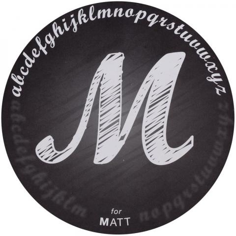 A matte finish with a capital "M" sketched with white ink into a black background. The alphabet in lowercase is drawn in an arch above the "M."